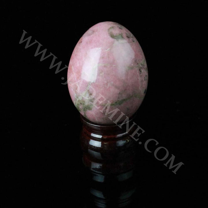 Pink rhodonite egg on a dark wooden stand