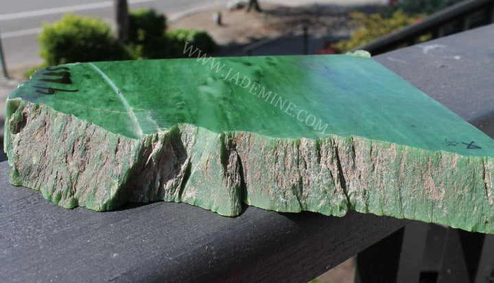 AA Siberian Rough jade slab with jagged base and glossy green surface on a railing