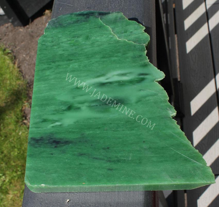 AA Siberian Rough jade slab with smooth polished top and rich green color on a railing