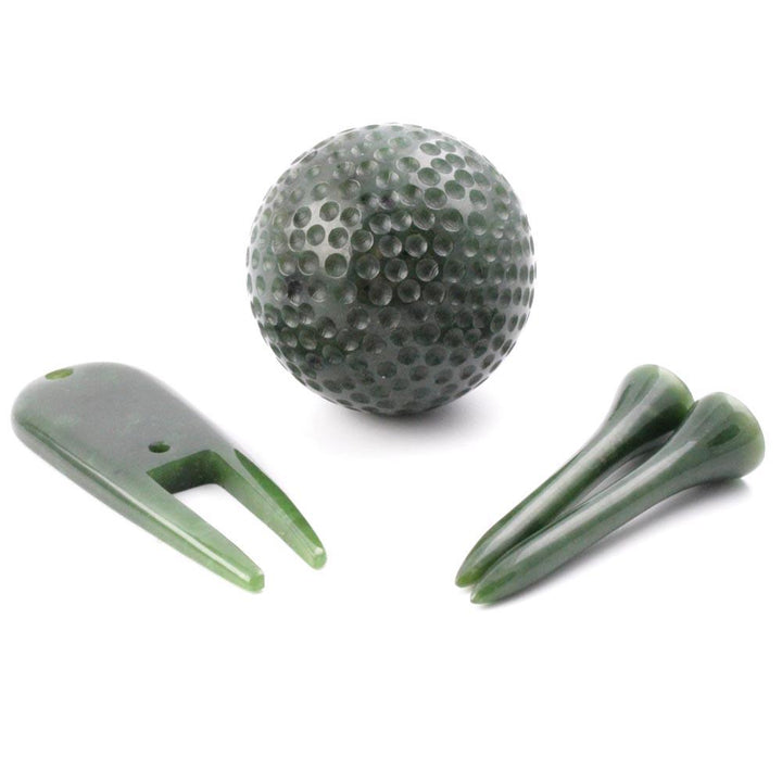 Green golf ball with two tees and a two-prong golf accessory on a white background