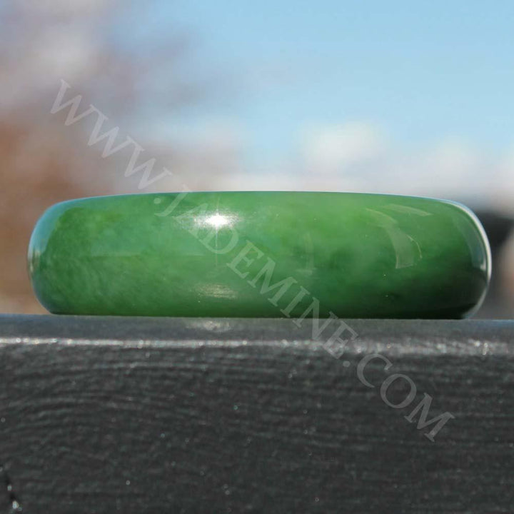 AA Siberian Jade Bangle 58x18mm close up on a dark wooden surface showing smooth finish