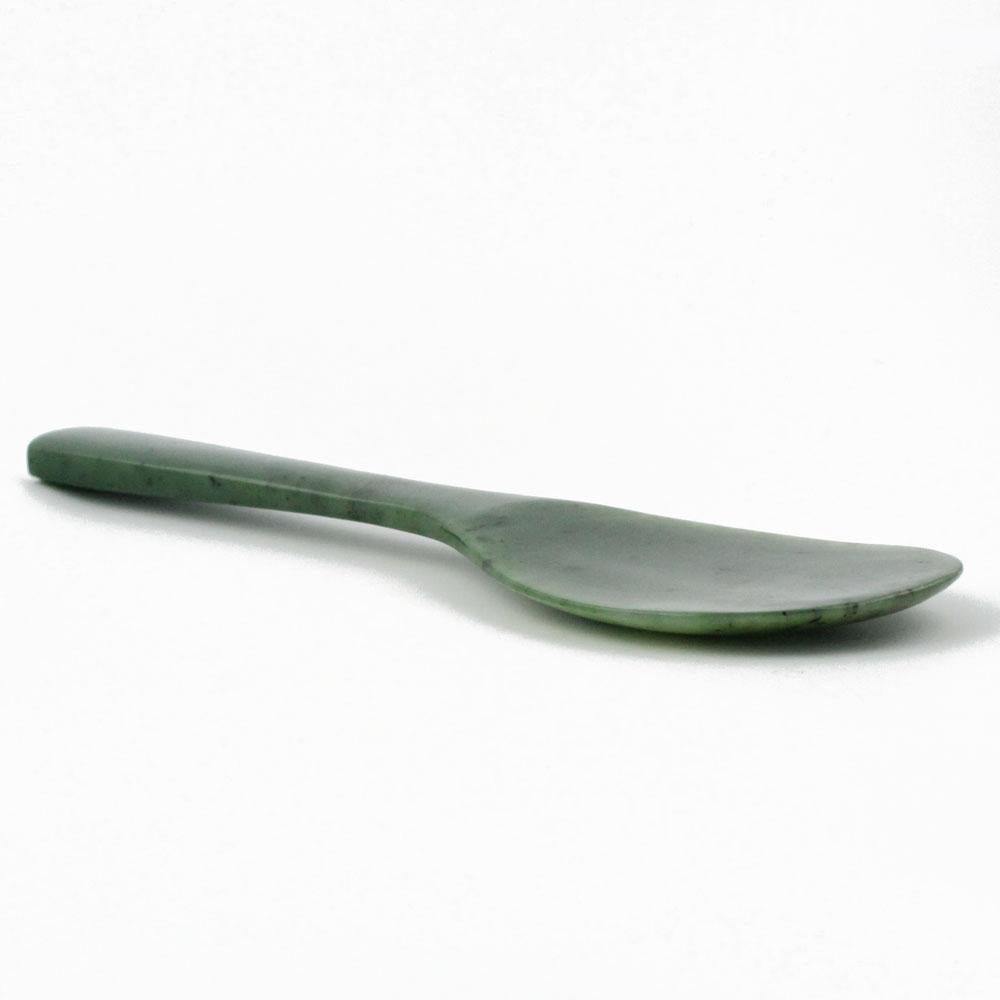Side view of jade rice spoon showing slender handle and wide shallow bowl