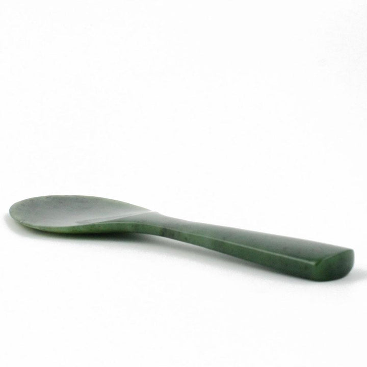 Side view of jade rice spoon with slender handle and oval bowl.
