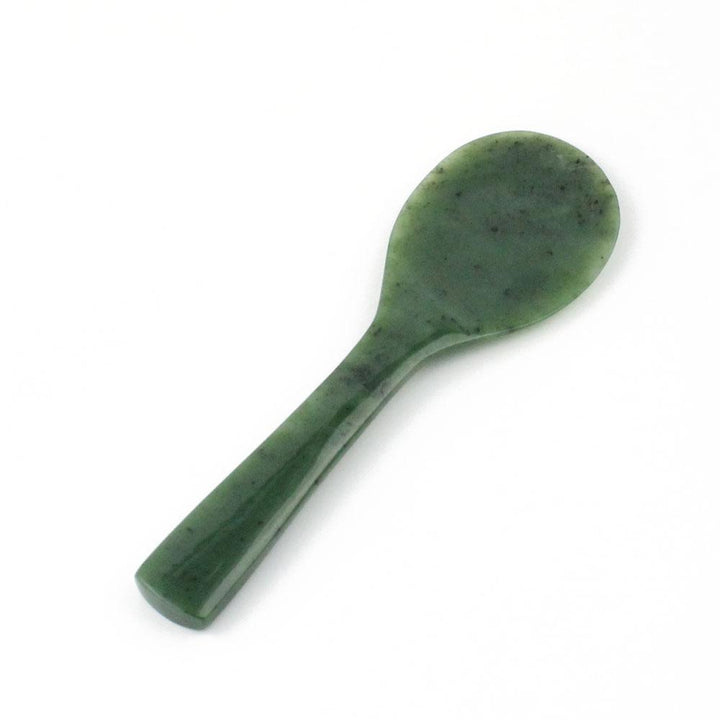 Close up of jade rice spoon bowl showing a rounded, green, speckled surface.