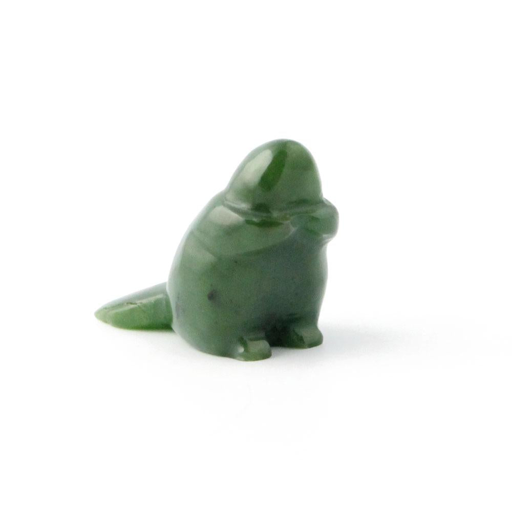 Small green beaver figurine sitting on a white surface