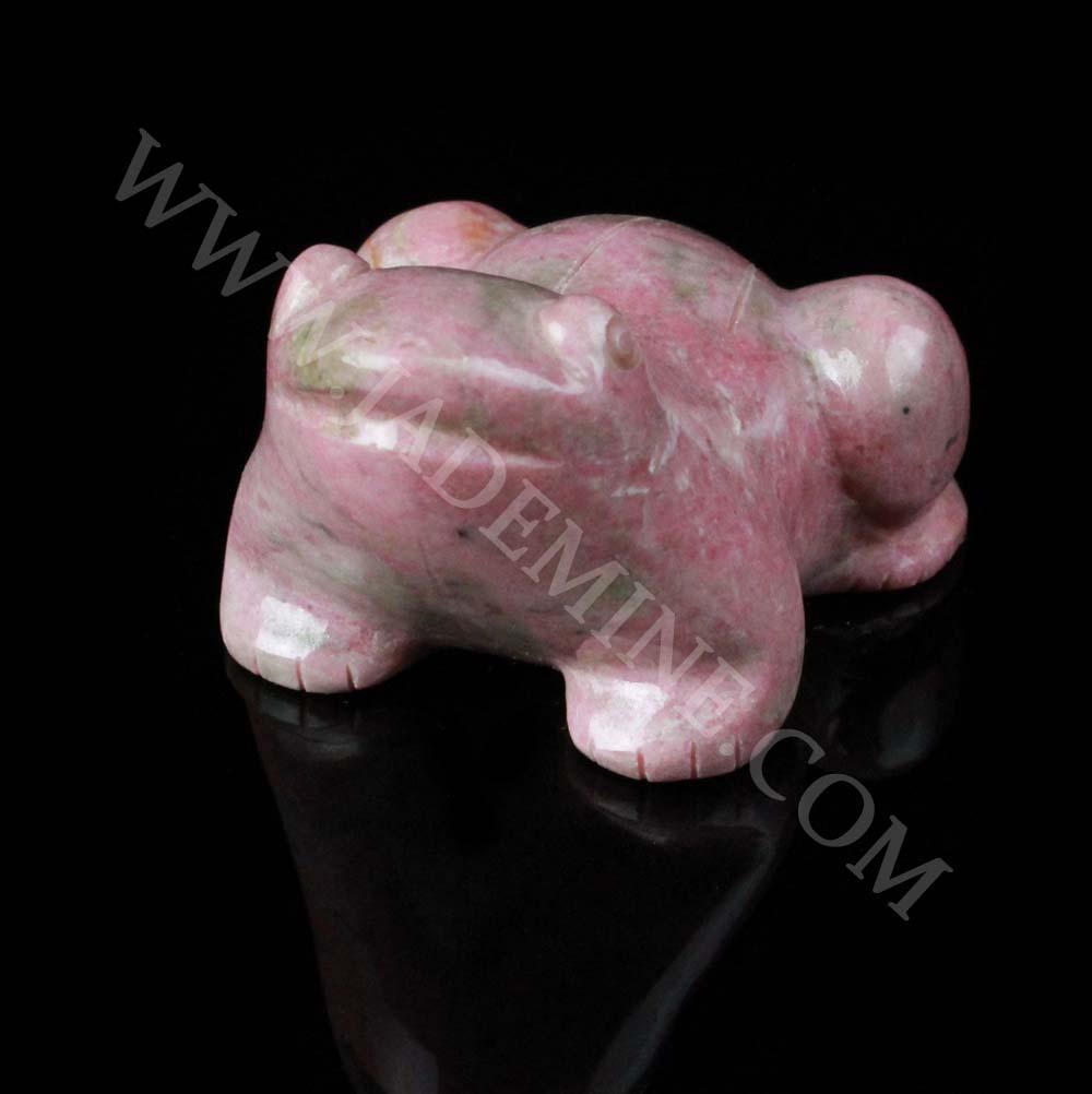 Pink rhodonite frog figurine on black surface viewed from the side