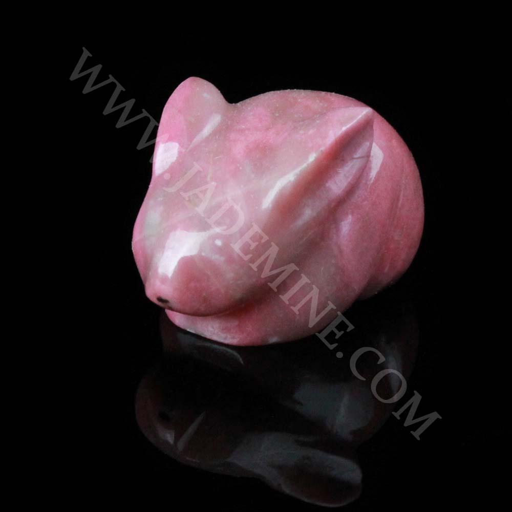 Pink rhodonite rabbit sculpture crouching on a black reflective surface