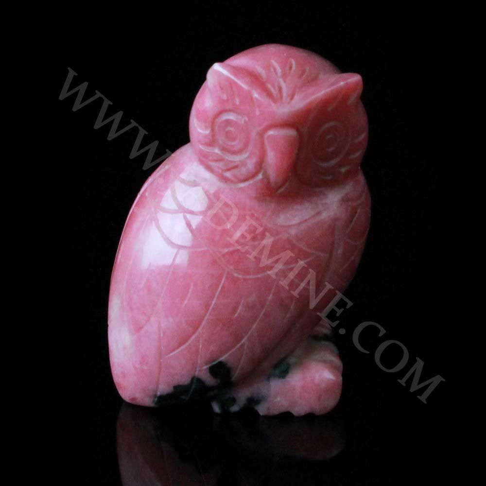 Pink rhodonite owl statue with carved feather details on a dark background