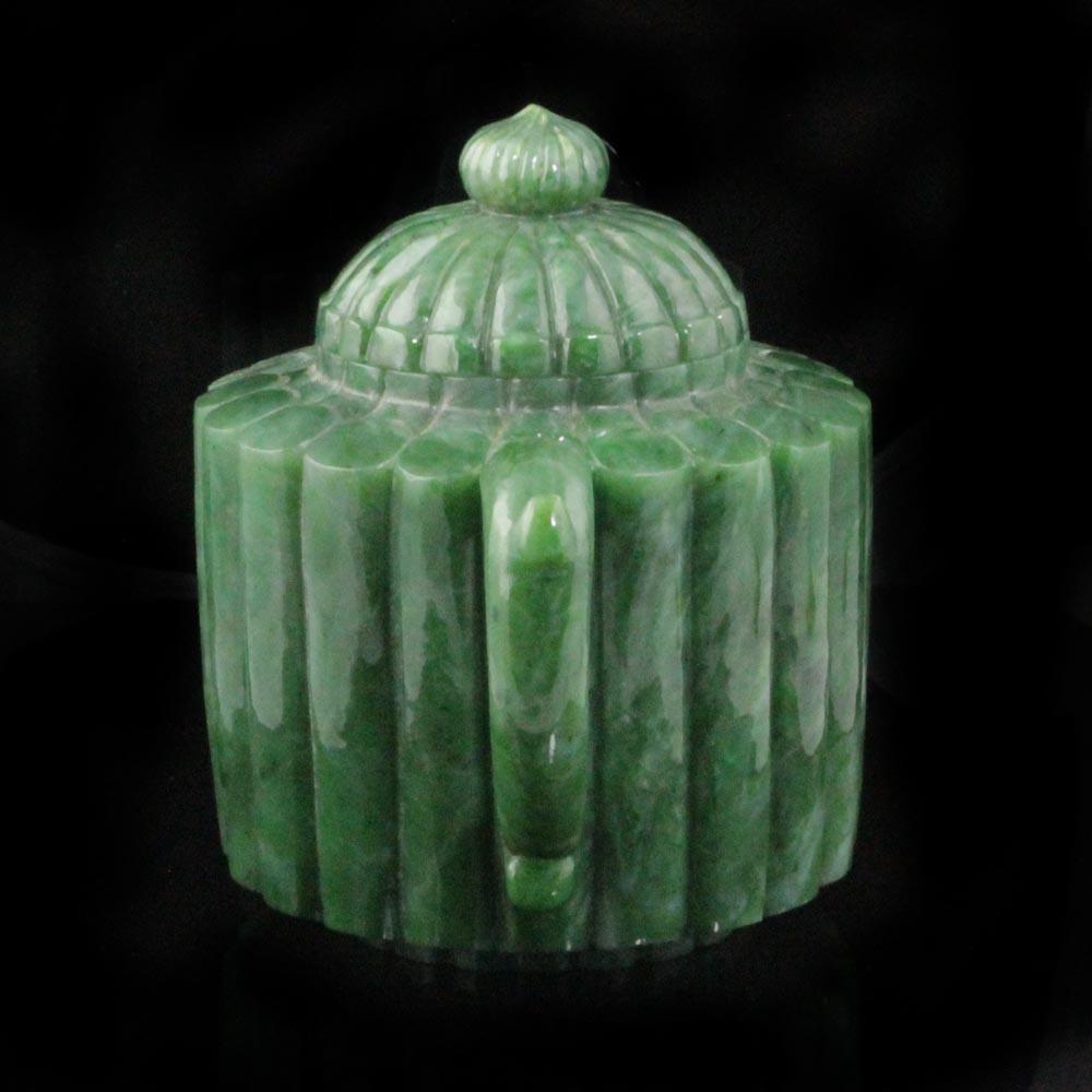 Angled view of jade teapot showing ribbed body lid and handle against a black background