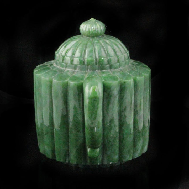 Angled view of jade teapot showing ribbed body lid and handle against a black background