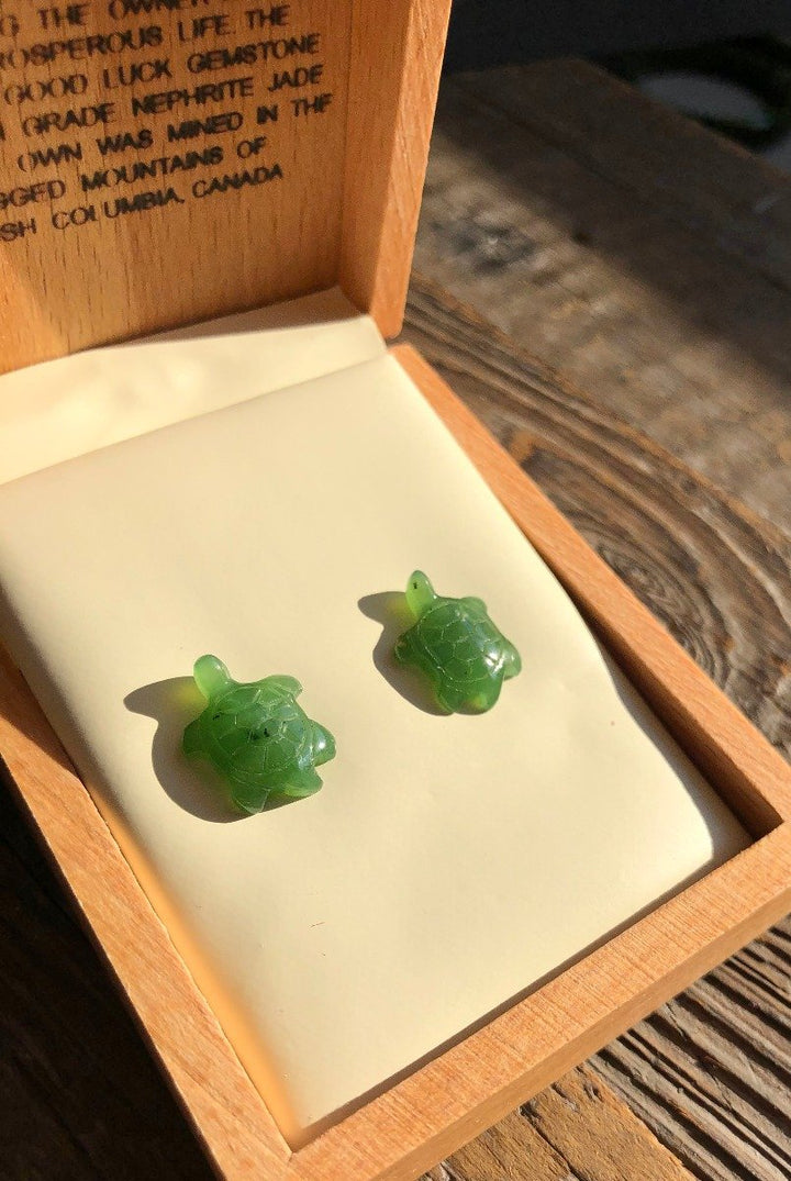 Green turtle shaped earrings displayed in a wooden box