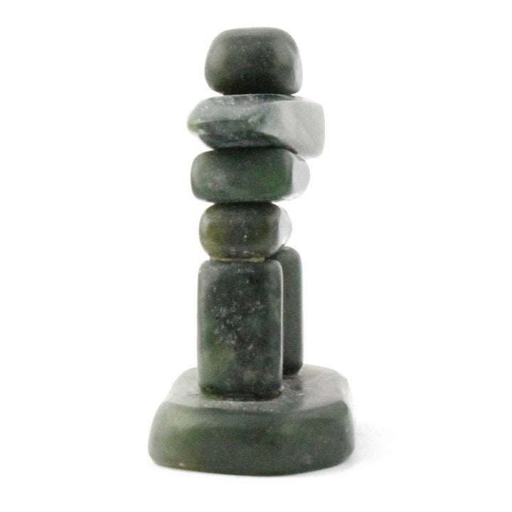 Tall green stone Inukshuk with stacked rocks a horizontal arm near the top and a rounded head.