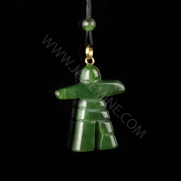 Green inukshuk pendant on a black cord against a black background