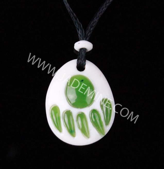 White bone pendant with green jade bear paw inlay on a black cord.