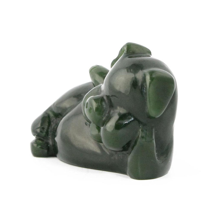 Dark green glossy pig figurine shown in side profile resting on its belly
