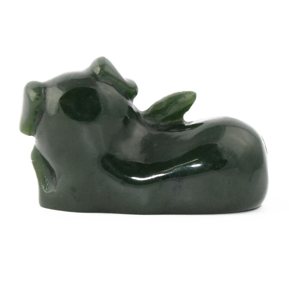 Dark green glossy pig figurine seen in a side view in a reclining pose
