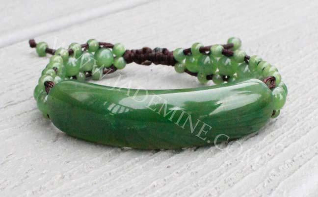 Bracelet 1833-12 with glossy curved green centerpiece and small round beads on dark cord