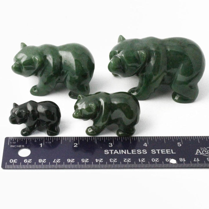 Group of green jade bear sculptures in different sizes with a ruler for scale