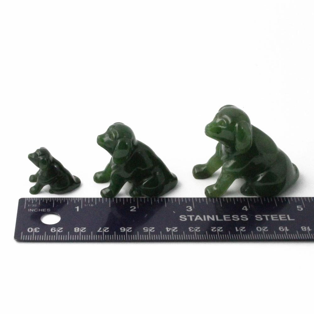 Set of three green jade Labrador retriever figurines with a ruler for scale on a white background
