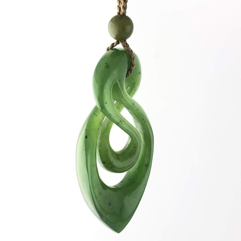 Close-up of green jade infinity twist pendant on a natural cord with bead, photographed against a white background.