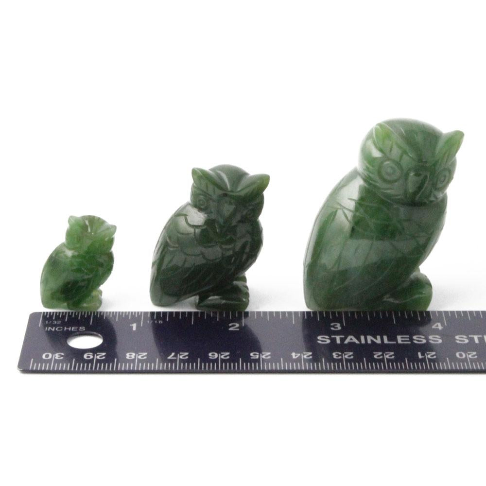 Three green owl figurines of varying sizes placed next to a ruler for scale