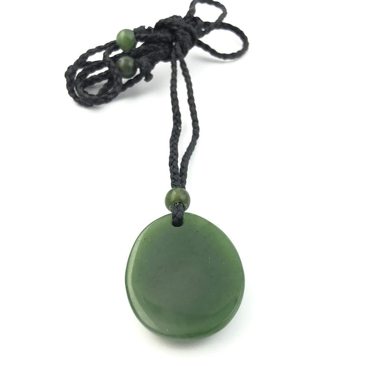 Green jade pendant on a black braided cord with a bead at the top