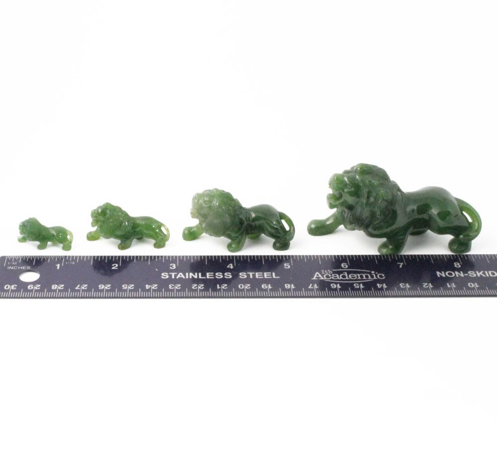 Series of green stone lion figurines in increasing sizes with a ruler for scale