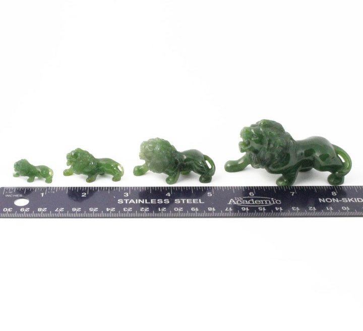 Series of green stone lion figurines in increasing sizes with a ruler for scale