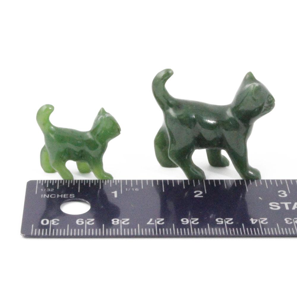 Two green cat figurines beside a measuring ruler for scale