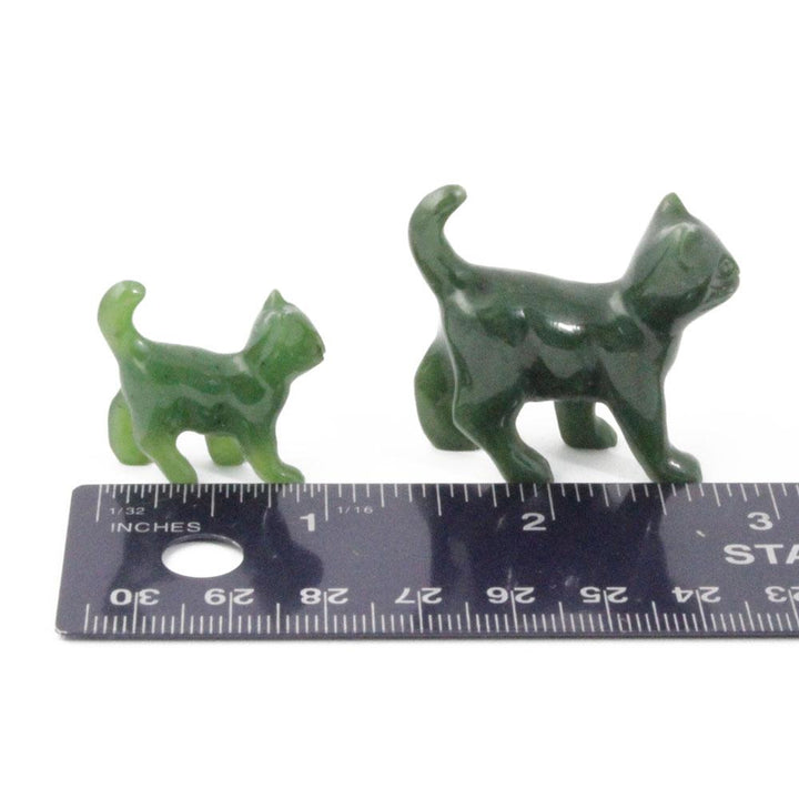 Two green cat figurines beside a measuring ruler for scale