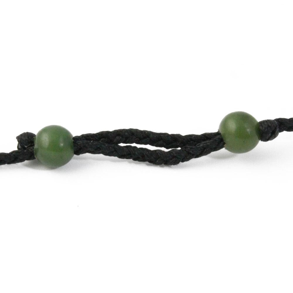 Dark braided cord bracelet with two green jade beads.