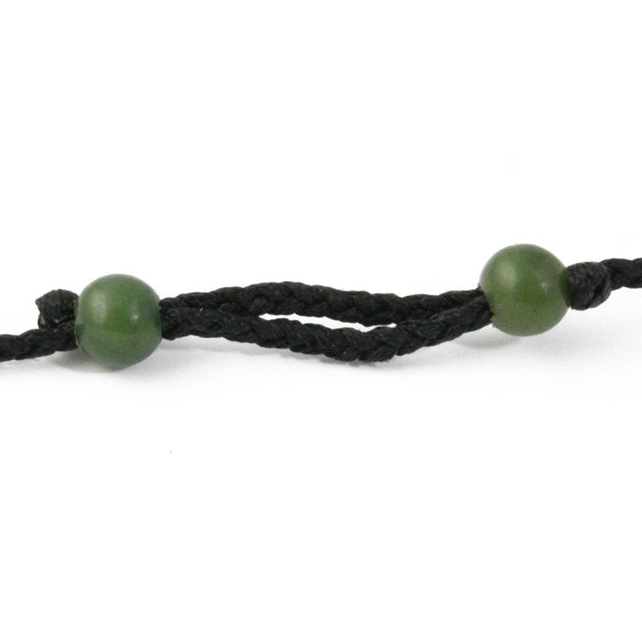 Dark braided cord bracelet with two green jade beads.