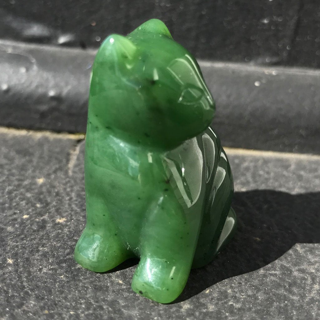 Green glossy sitting cat figurine on a dark surface