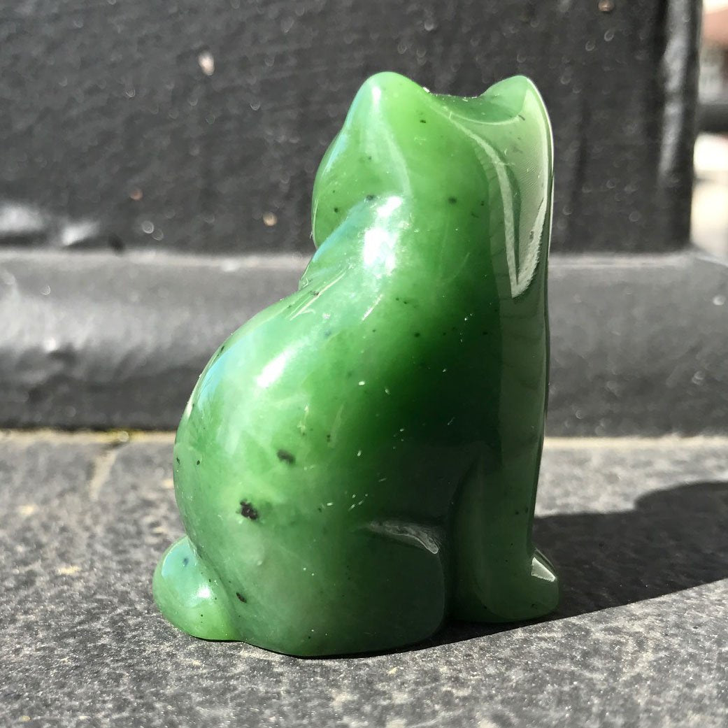 Back view of two green jade cat sculptures showing their rounded forms