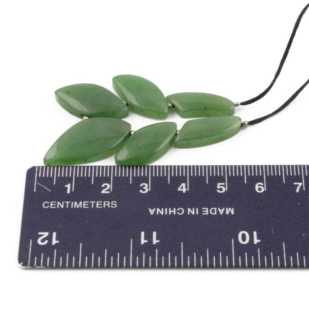 Close up of green jade leaf beads on a black cord with a ruler for scale