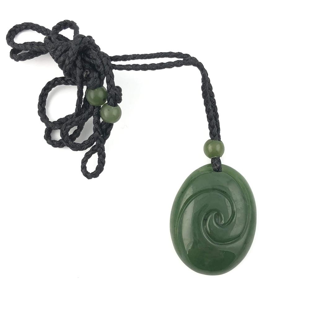 Dark green jade pendant with a circular spiral carving on a black braided cord and green beads.