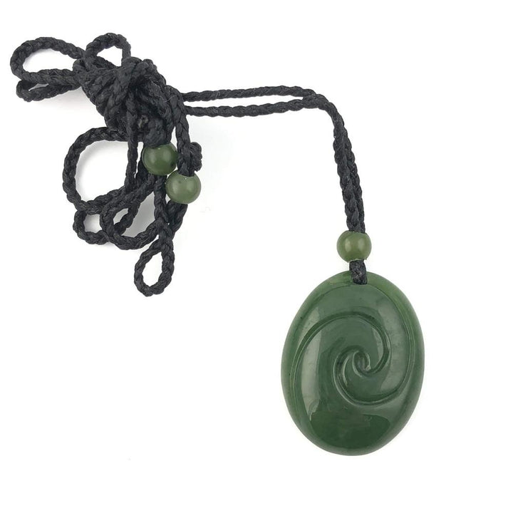 Dark green jade pendant with a circular spiral carving on a black braided cord and green beads.