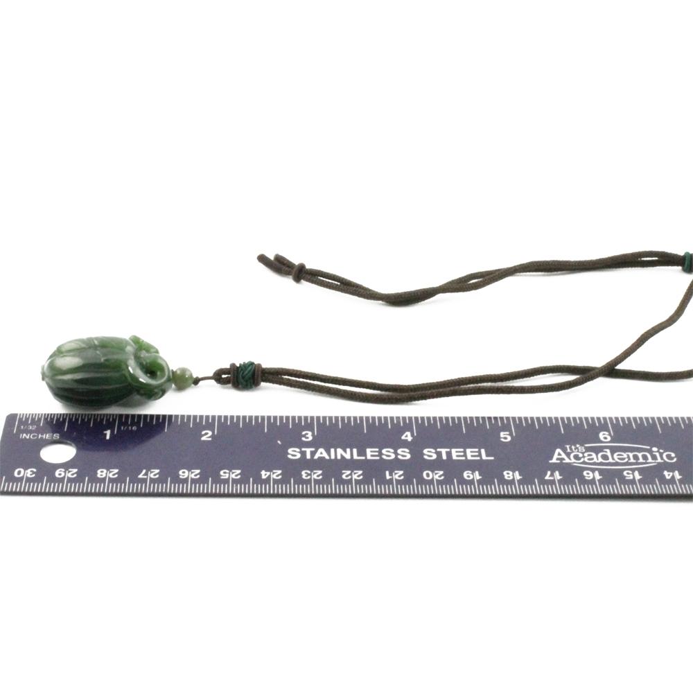 Green jade squash pendant carved with leaf pattern on brown cord necklace.