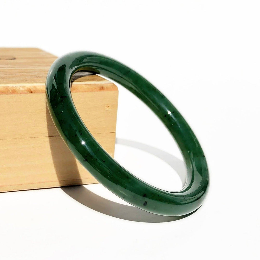 Child size jade bangle 45mm displayed on a wooden block in dark green