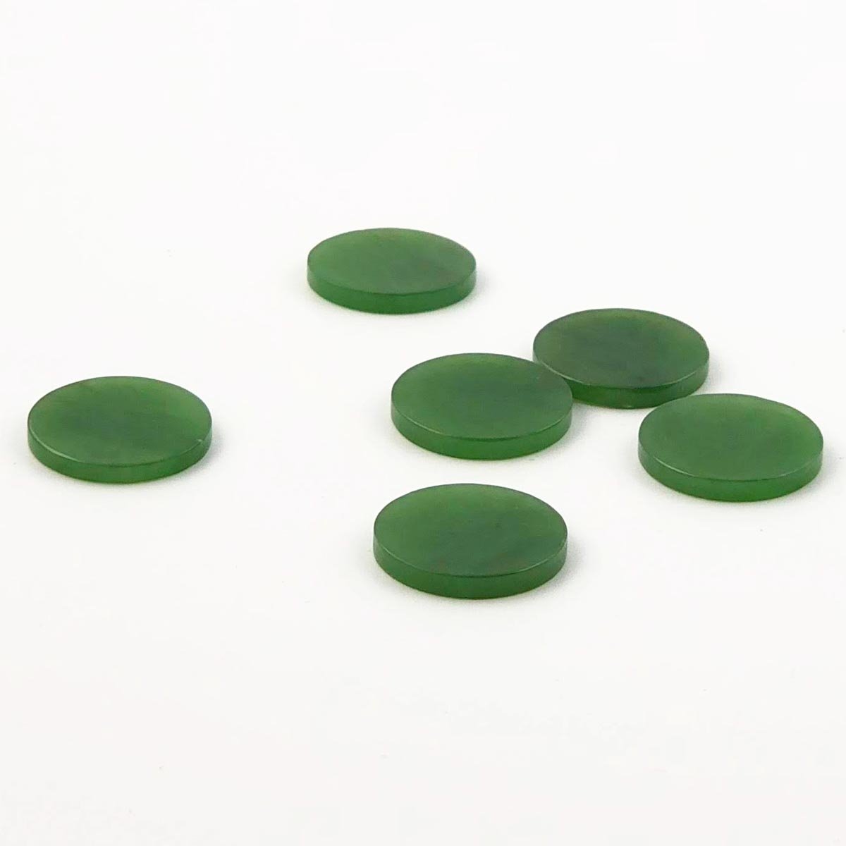 Green round flat cabochons laid out on a white background