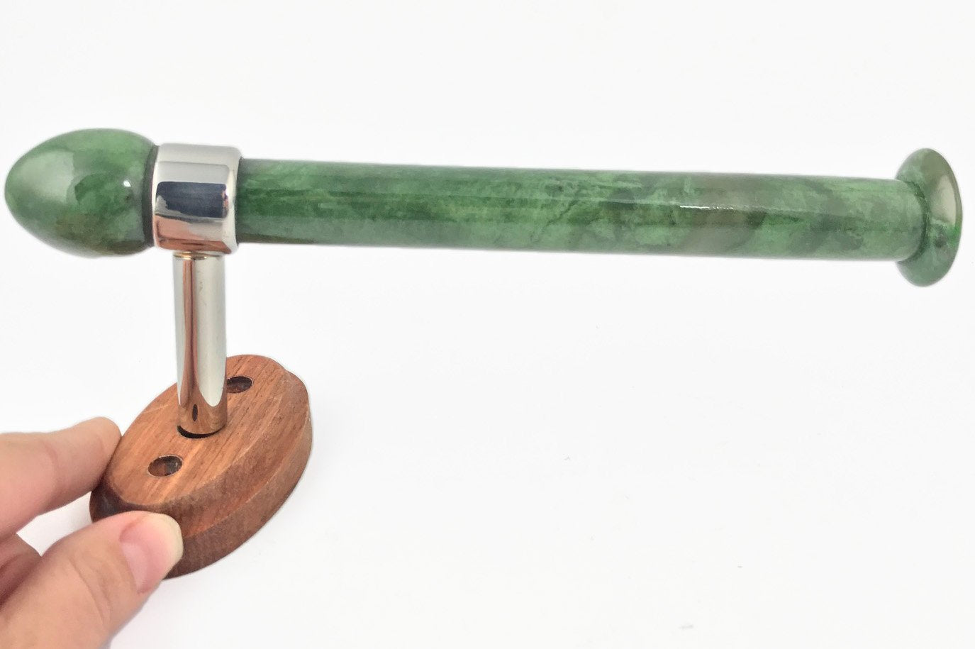 Green marble toilet paper holder with a long cylindrical rod mounted on a wooden base and chrome bracket