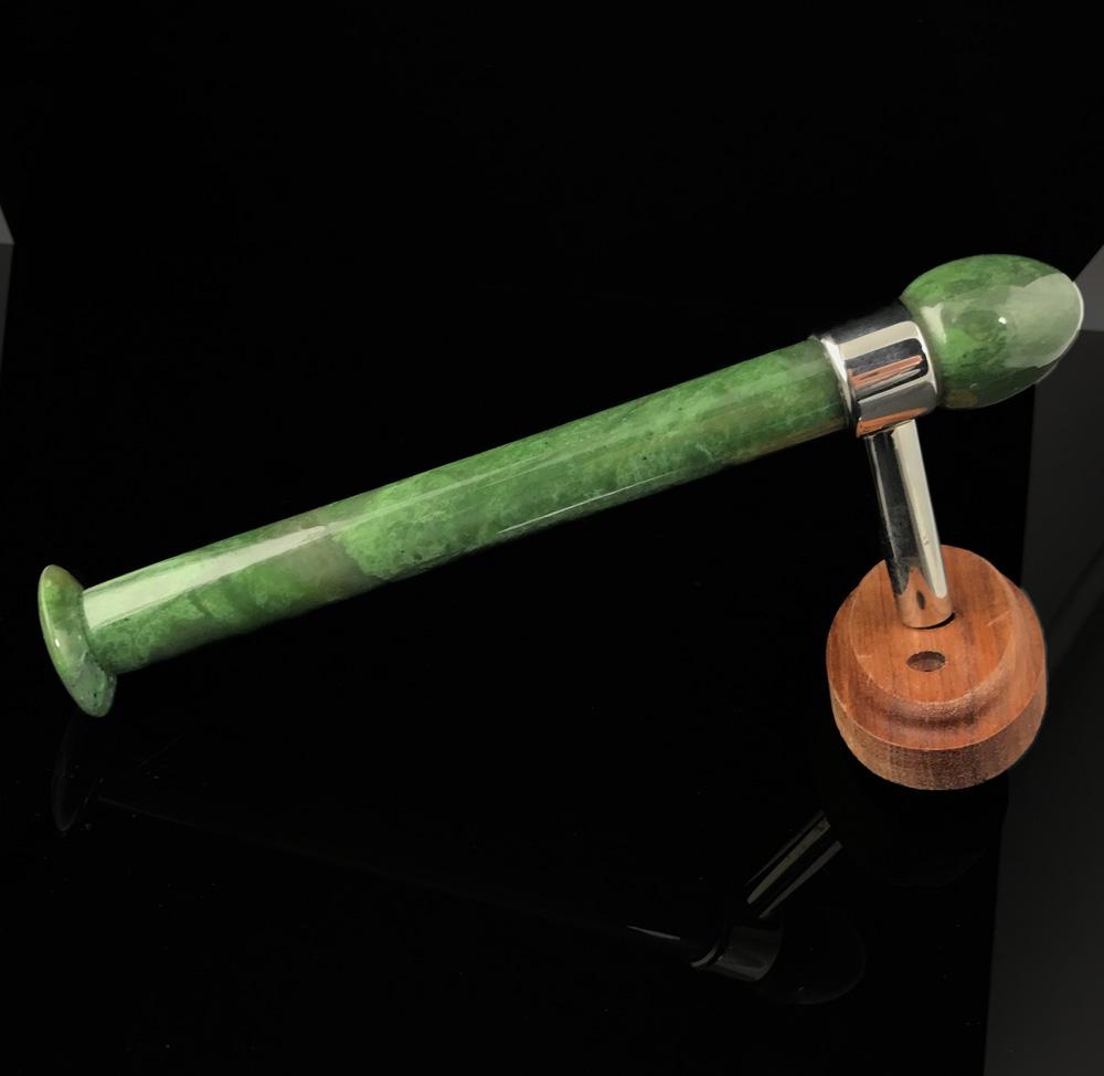 Green marble toilet paper holder with metal arm and round wooden base.