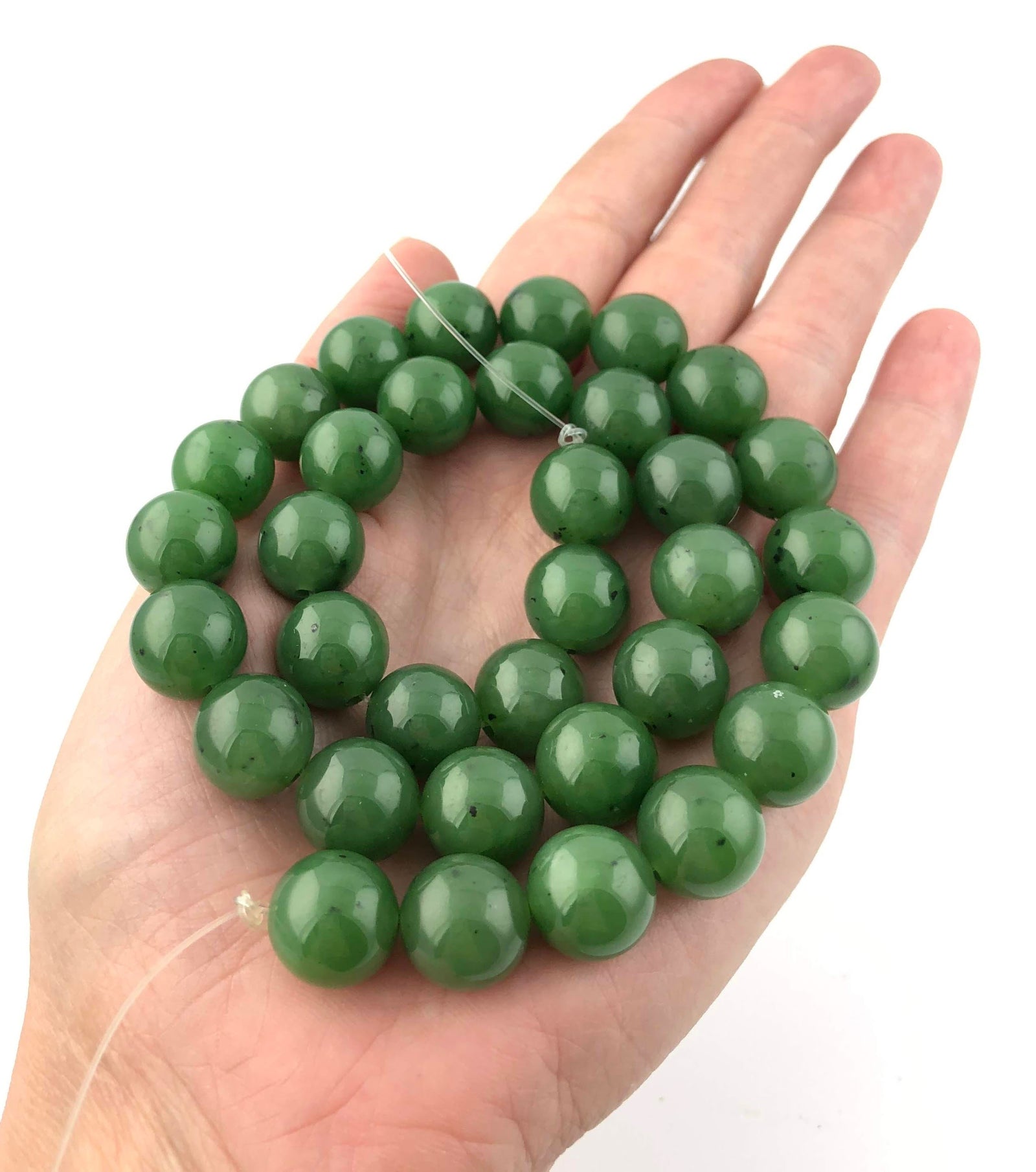 A handful of green 12mm beads unstrung held in the palm