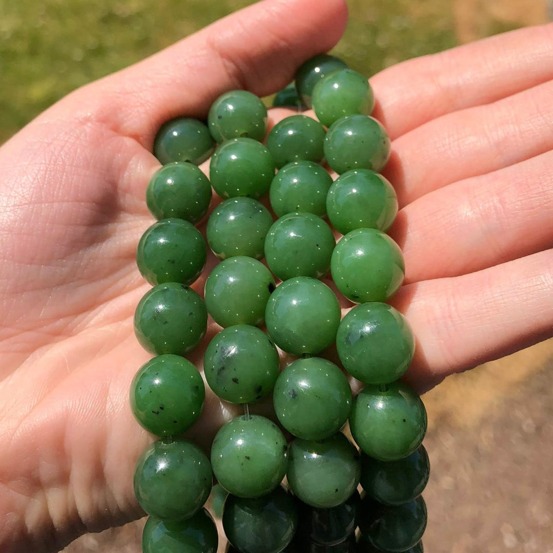 Handful of 12mm green jade beads in a palm, unstrung