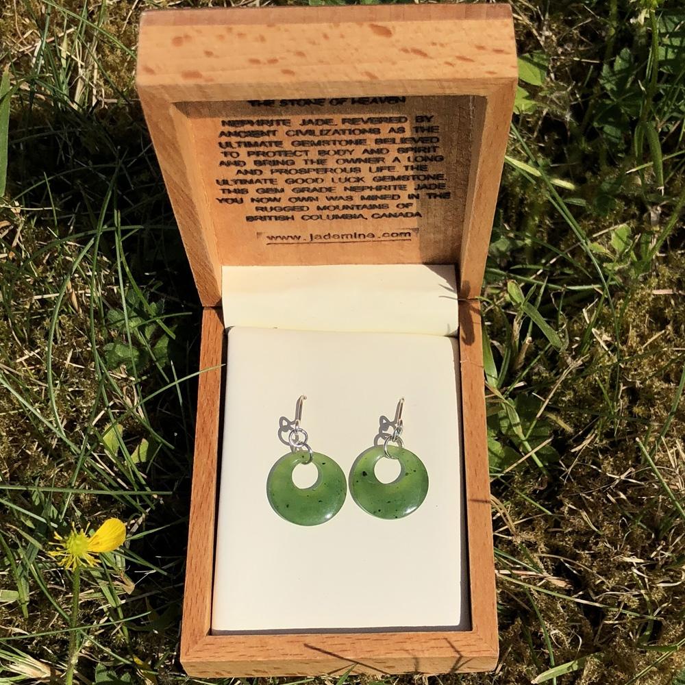Pair of green circular jade hoop earrings in an open wooden box