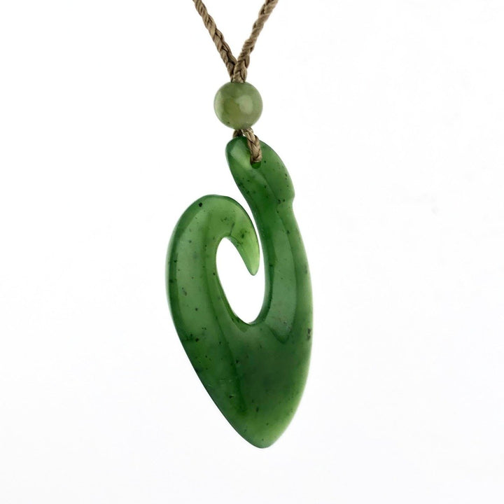 Canadian Jade fish hook pendant on a braided tan cord with a small round bead above.