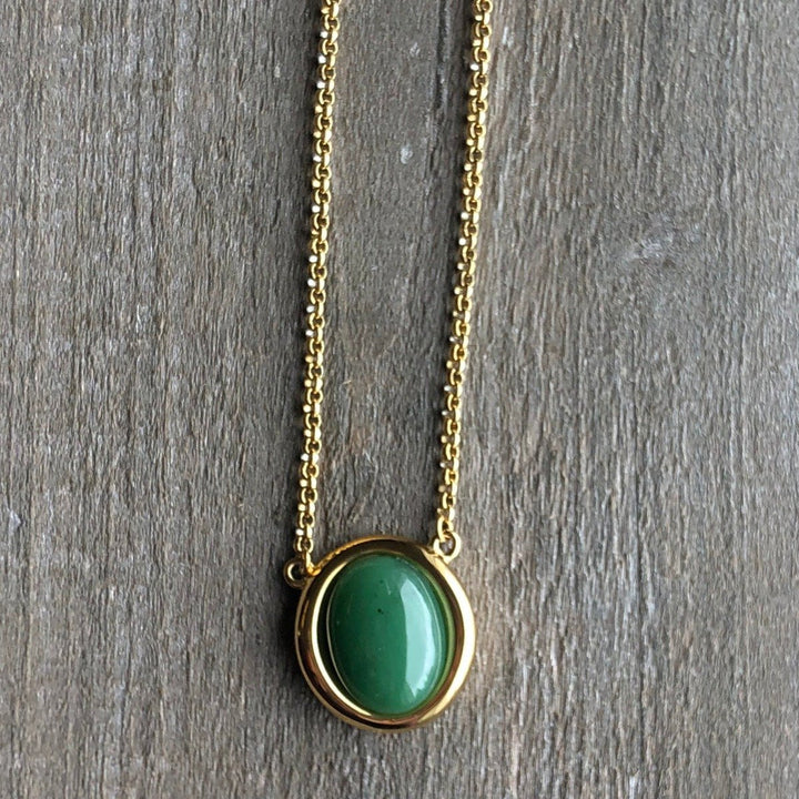 Gold-tone chain necklace featuring a round green jade pendant in a gold bezel
