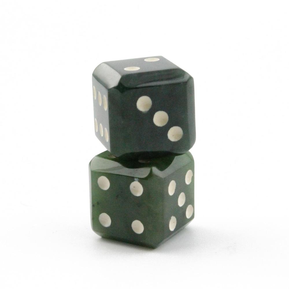 Two green dice with white pips stacked on a weathered wooden surface.