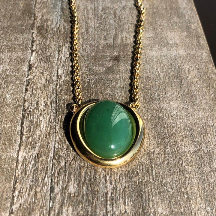 Close-up view of the green jade pendant set in a gold bezel on a chain