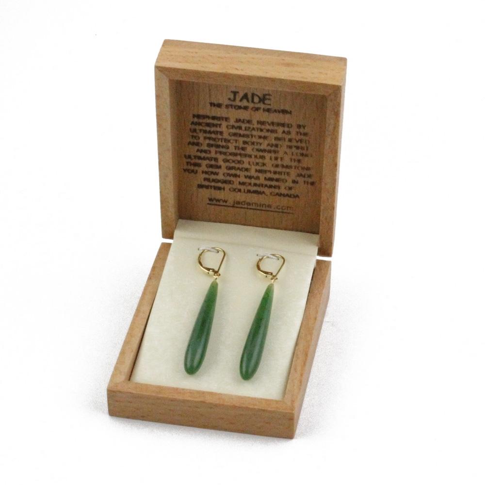Open wooden jewelry box showing long jade drop earrings with gold lever-back closures.